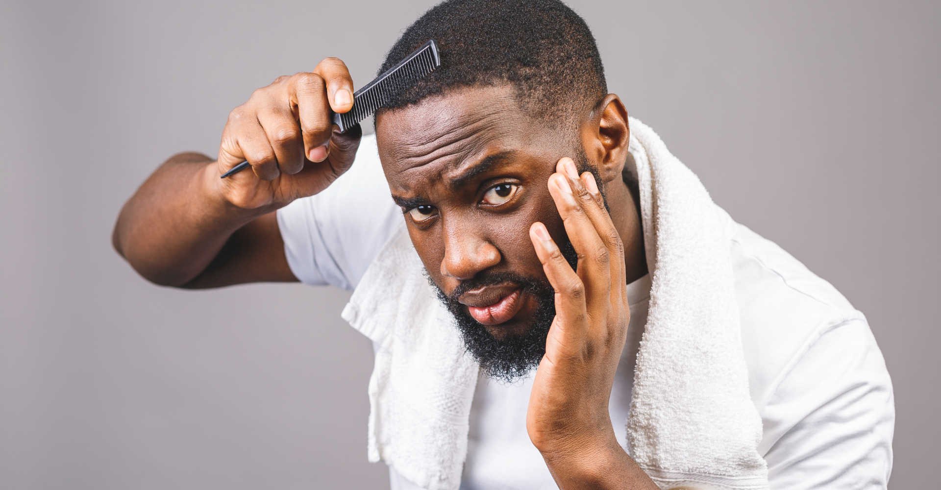 Modelo negro passando pente em seu cabelo com corte baixo